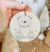 a hand holding a christmas ornament with a teddy bear on it
