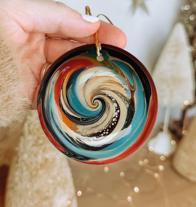 a hand holding a glass ornament with a swirl design