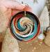a hand holding a glass ornament with a swirl design