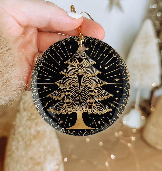 a hand holding a black and gold christmas ornament