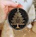 a hand holding a black and gold christmas ornament