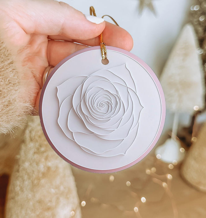 a person holding a paper rose ornament in their hand