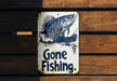 a gone fishing sign hanging on a wooden wall