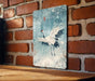 a picture of a white bird on a brick wall