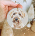 a hand holding a christmas ornament with a picture of a dog
