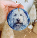 a person holding a blue ornament with a white dog on it