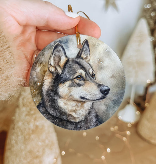 a hand holding a christmas ornament with a picture of a wolf on it