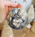 a hand holding a christmas ornament with a picture of a wolf on it