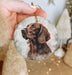 a person holding a christmas ornament with a dog on it