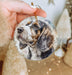 a hand holding a christmas ornament with a picture of a dog