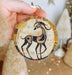 a hand holding a ceramic ornament with a picture of a deer