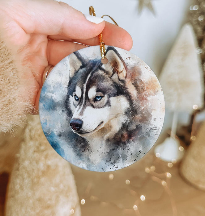 a hand holding a ornament with a picture of a husky