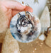 a hand holding a ornament with a picture of a husky