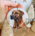 a hand holding a christmas ornament with a dog on it
