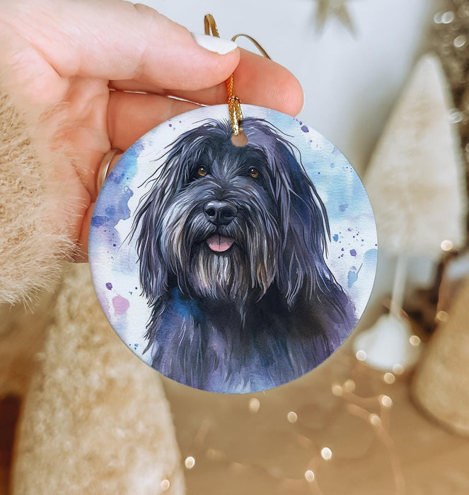a hand holding a round ornament with a black dog on it