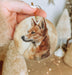 a hand holding a small ornament with a picture of a dog on it