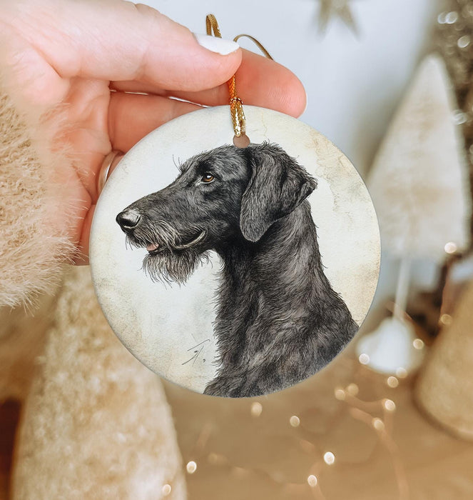 a hand holding a christmas ornament with a black dog on it