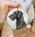 a hand holding a christmas ornament with a black dog on it