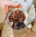 a hand holding a christmas ornament with a dog on it
