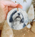 a hand holding a round ornament with a picture of a dog