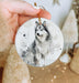 a hand holding a ceramic ornament with a picture of a dog