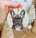 a hand holding a ceramic ornament with a picture of a dog