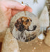 a hand holding a round ornament with a picture of a dog on it