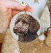 a hand holding a christmas ornament with a picture of a dog