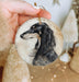 a hand holding a christmas ornament with a dog on it