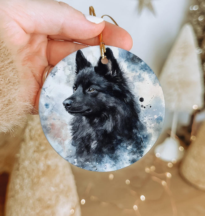 a hand holding a round ornament with a black dog on it