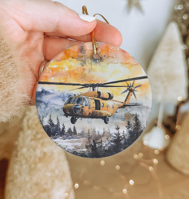 a hand holding a christmas ornament with a helicopter on it