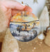 a hand holding a christmas ornament with a helicopter on it