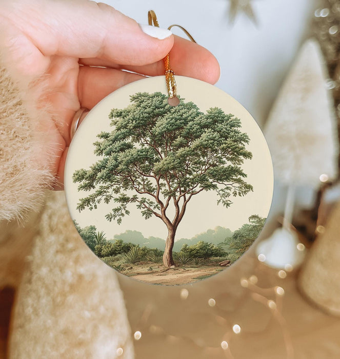 a hand holding a christmas ornament with a tree on it