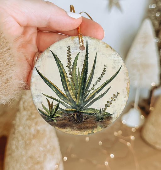 a hand holding a glass ornament with a plant on it