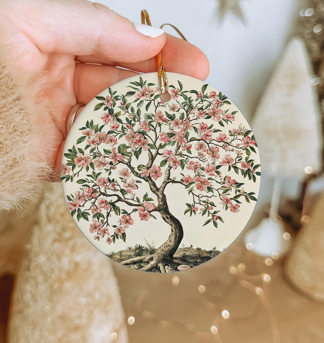 a hand holding a ceramic ornament with a tree on it