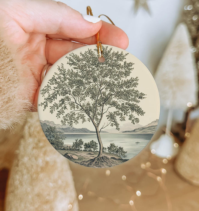 a person holding a christmas ornament with a tree on it