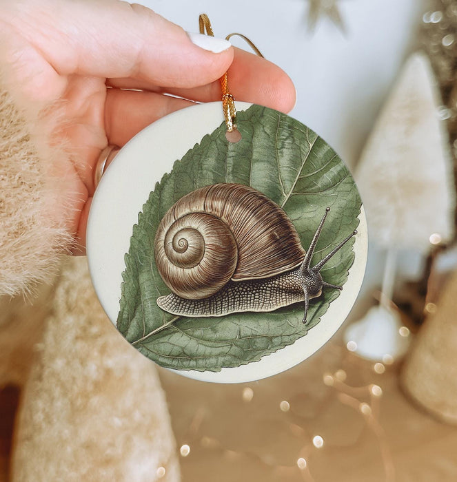 a hand holding a ceramic ornament with a snail on it