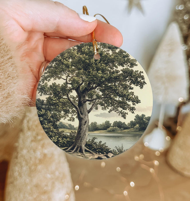 a person holding a christmas ornament with a tree on it