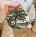 a person holding a christmas ornament with a tree on it