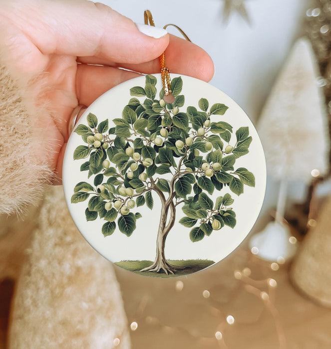a person holding a christmas ornament with a tree on it