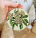 a person holding a round ornament with flowers on it