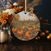 a ceramic ornament with a painting of pumpkins on it