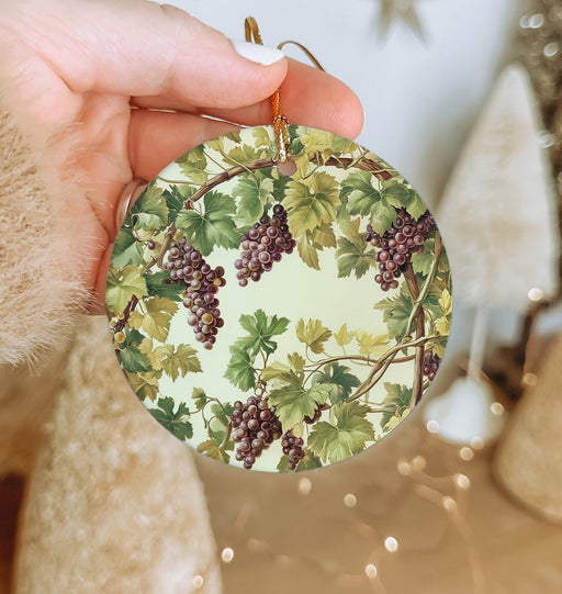 a person holding a christmas ornament with grapes on it