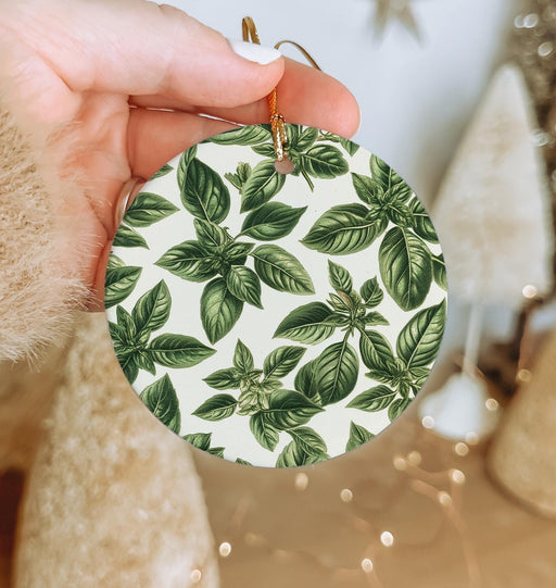 a person holding a christmas ornament with green leaves on it