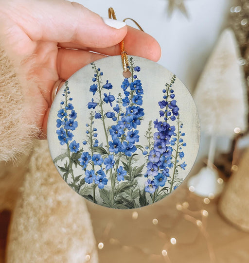 a hand holding a round ornament with blue flowers