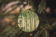 a green ornament hanging from a pine tree