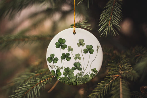 a white ornament with four leaf clovers hanging from a tree