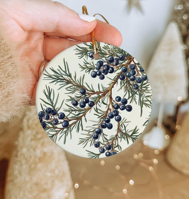 a person holding a christmas ornament with berries on it