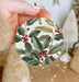 a person holding a christmas ornament in their hand
