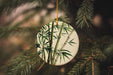a ceramic ornament hanging from a pine tree